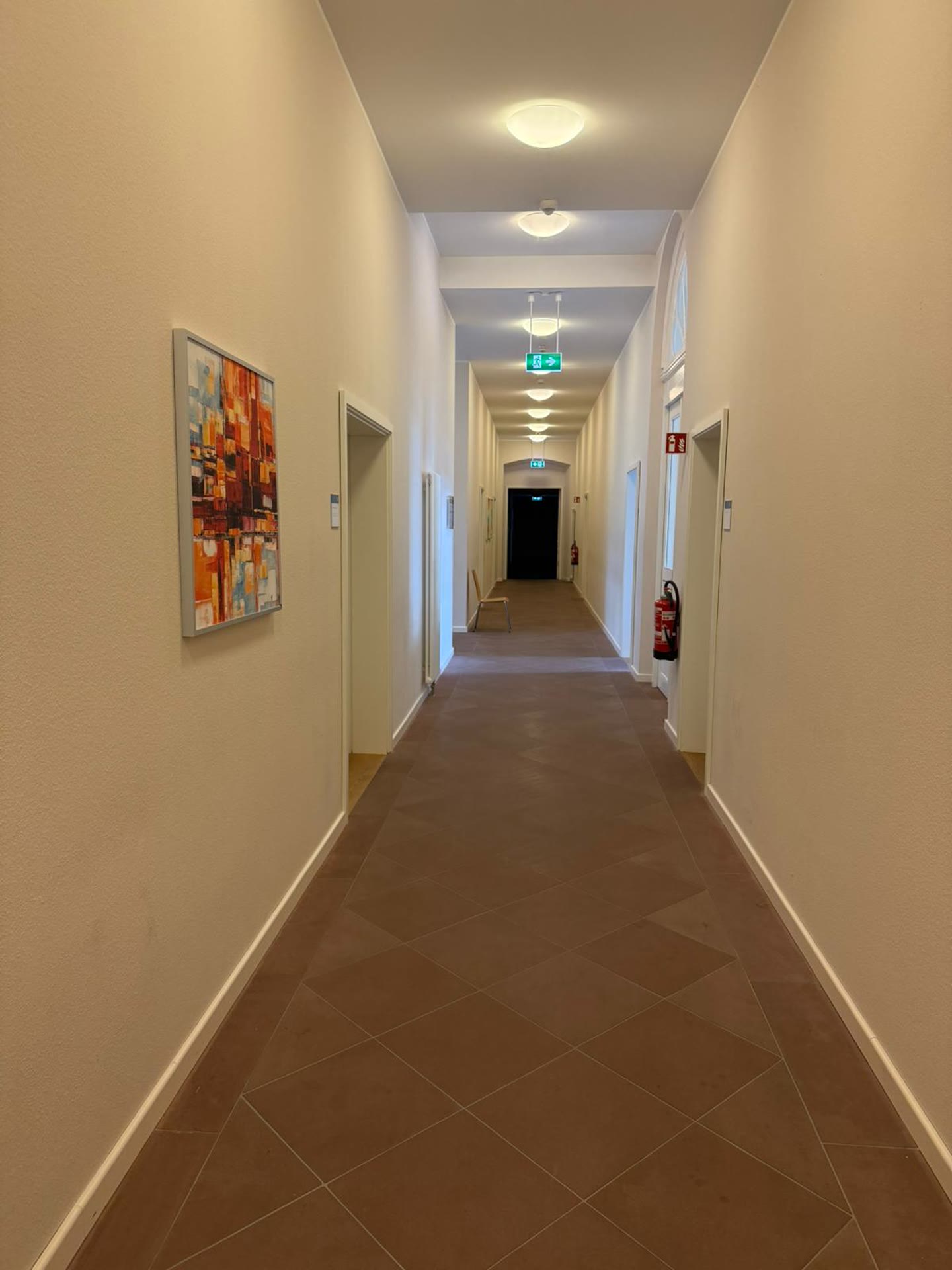 Heller Klinikflur nach der Sanierung mit Kunst an der Wand und moderner Beleuchtung