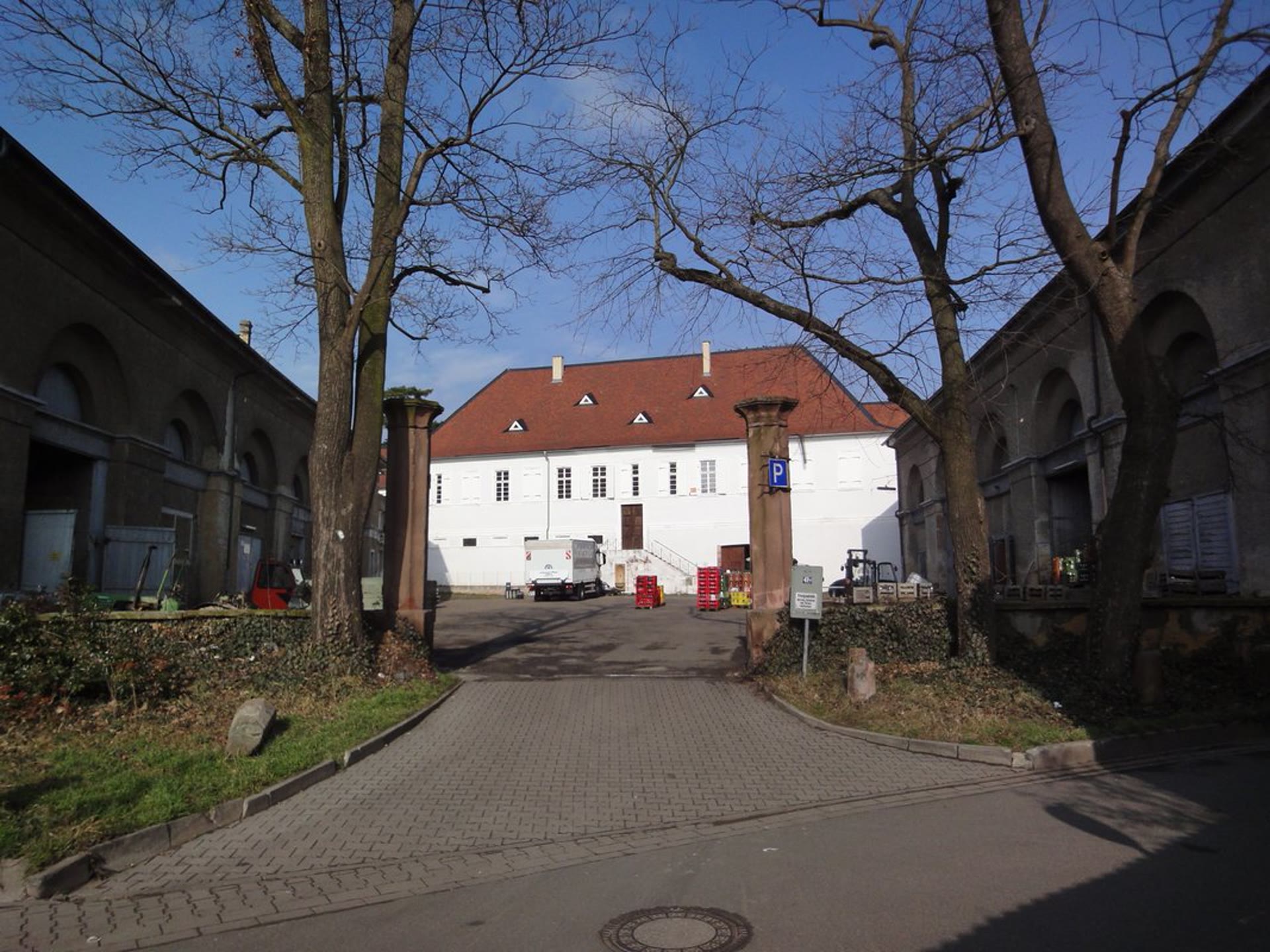 Innenhof vor der Sanierung mit Fahrzeugen, Getränkekisten und unsanierten Remisen