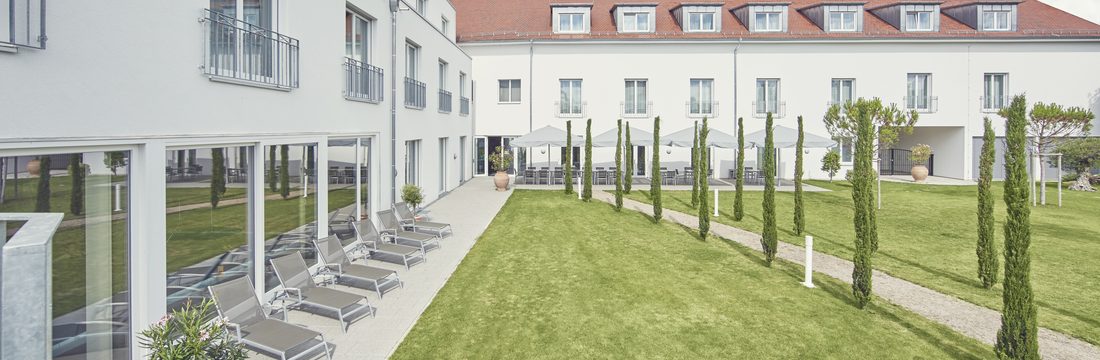 Liegestühle auf der Terrasse entlang der Rasenfläche im Innenhof