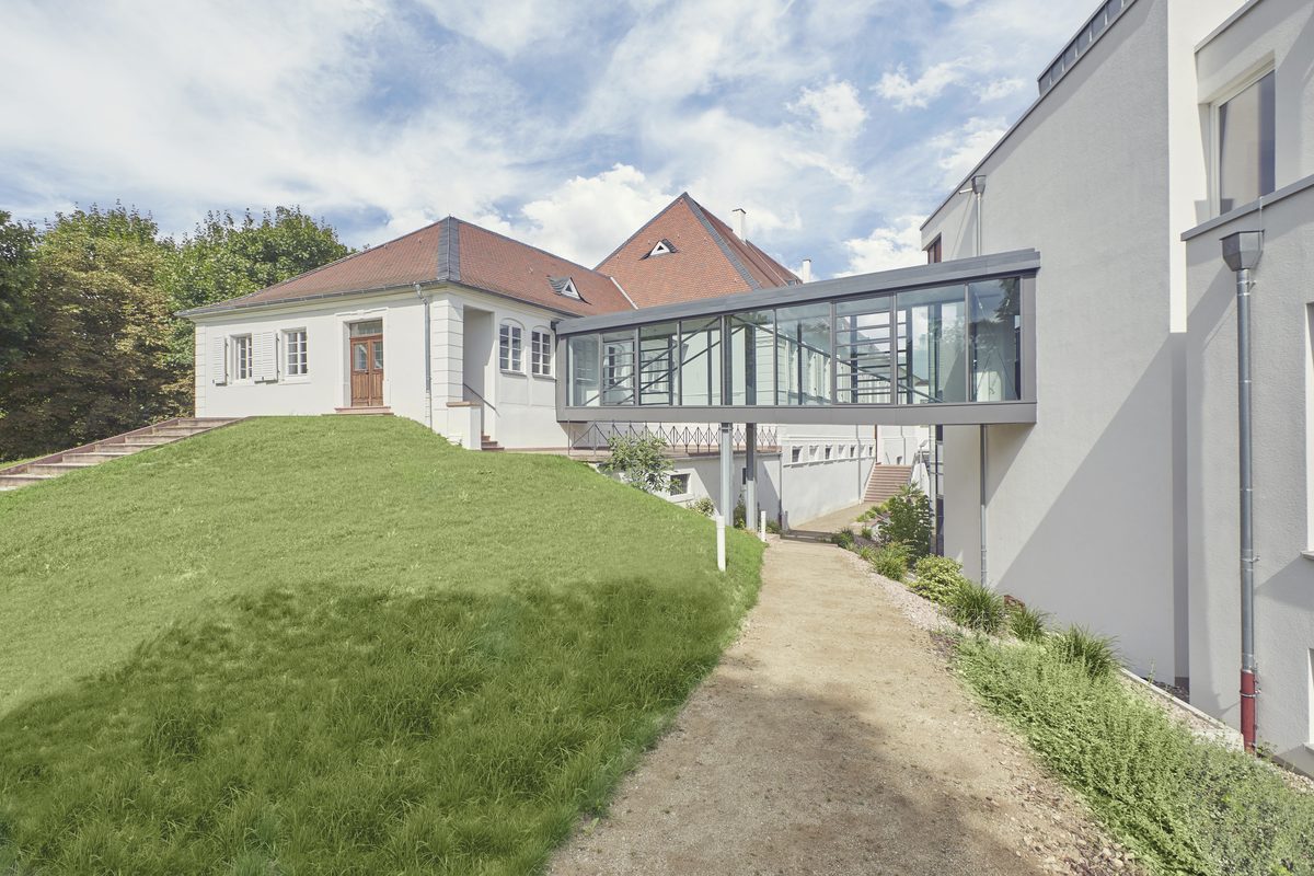 Historischer Klinikflügel, über einen verglasten Gang mit dem Neubau verbunden