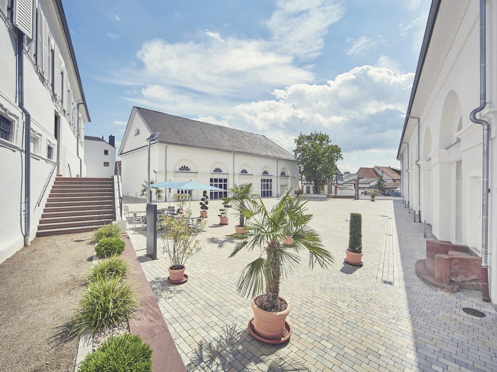 Gepflasterter Schlosshof mit Kübelpflanzen und Sitzgelegenheiten